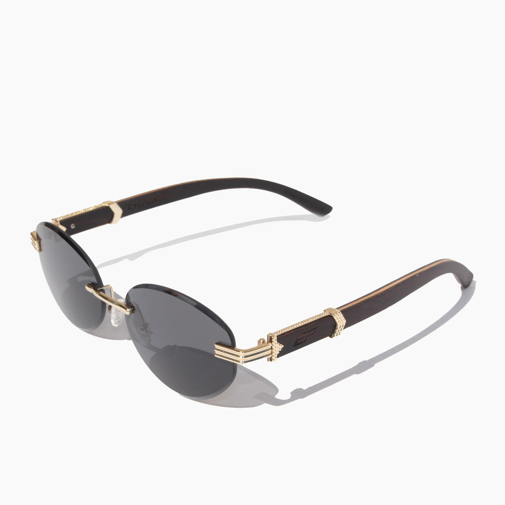 EyeFend Prime rimless oval sunglasses with dark grey lenses, a gold metal bridge, and dark wood temples