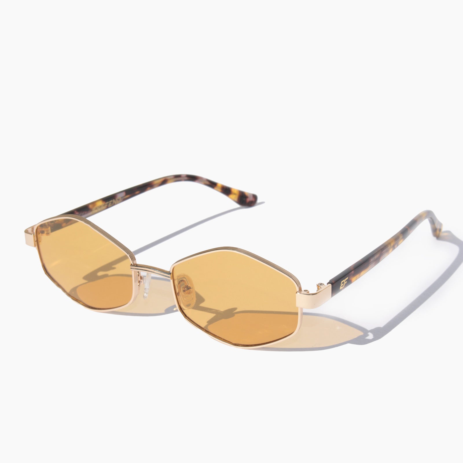 EyeFend Smart sunglasses featuring gold geometric hexagonal frames with yellow amber tinted polarized lenses and tortoiseshell acetate temple arms.